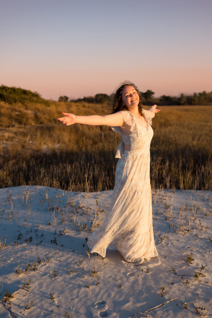 color photo of a girl with her arms outstretched on the beach on Topsail Island, NC