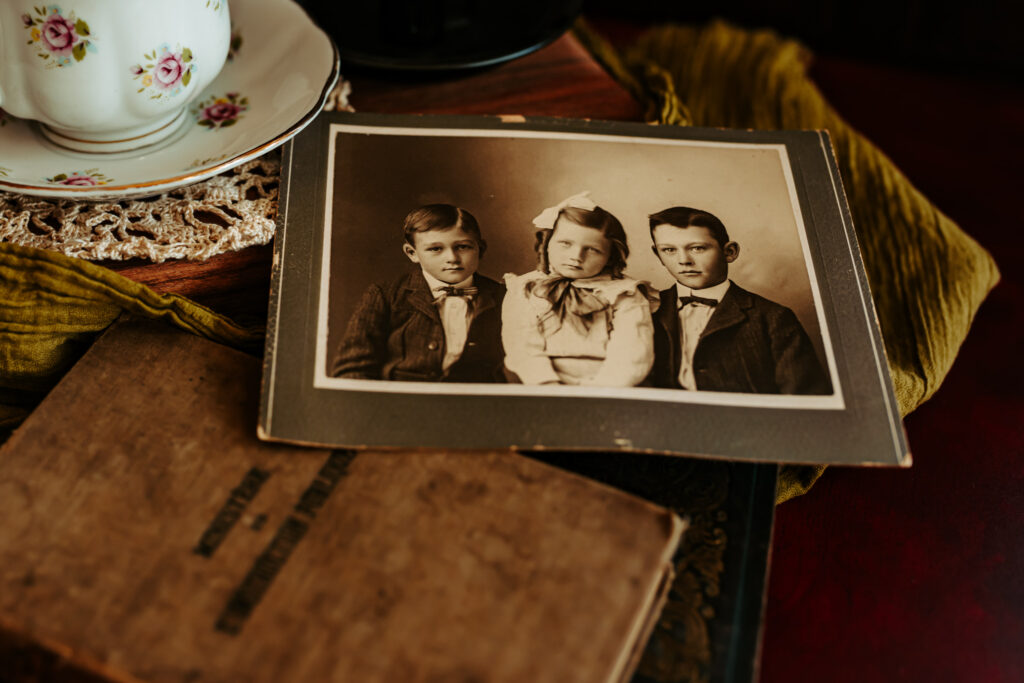 Old photograph of children taken long ago, laying on a table with a tea cup and old book.