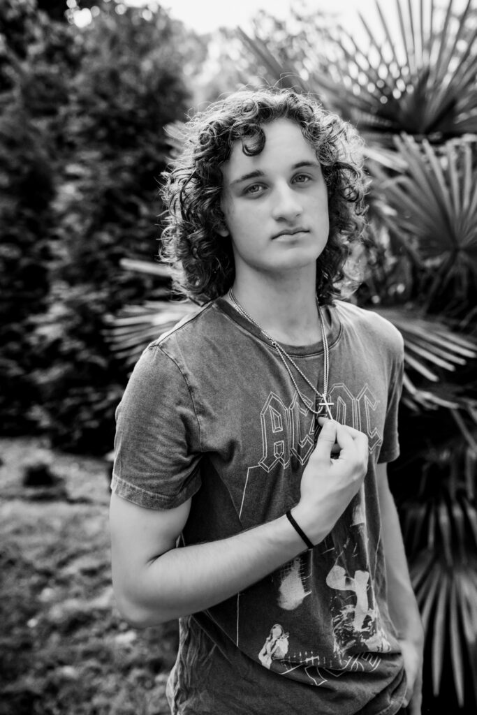 black and white photo af a young man holding his necklace