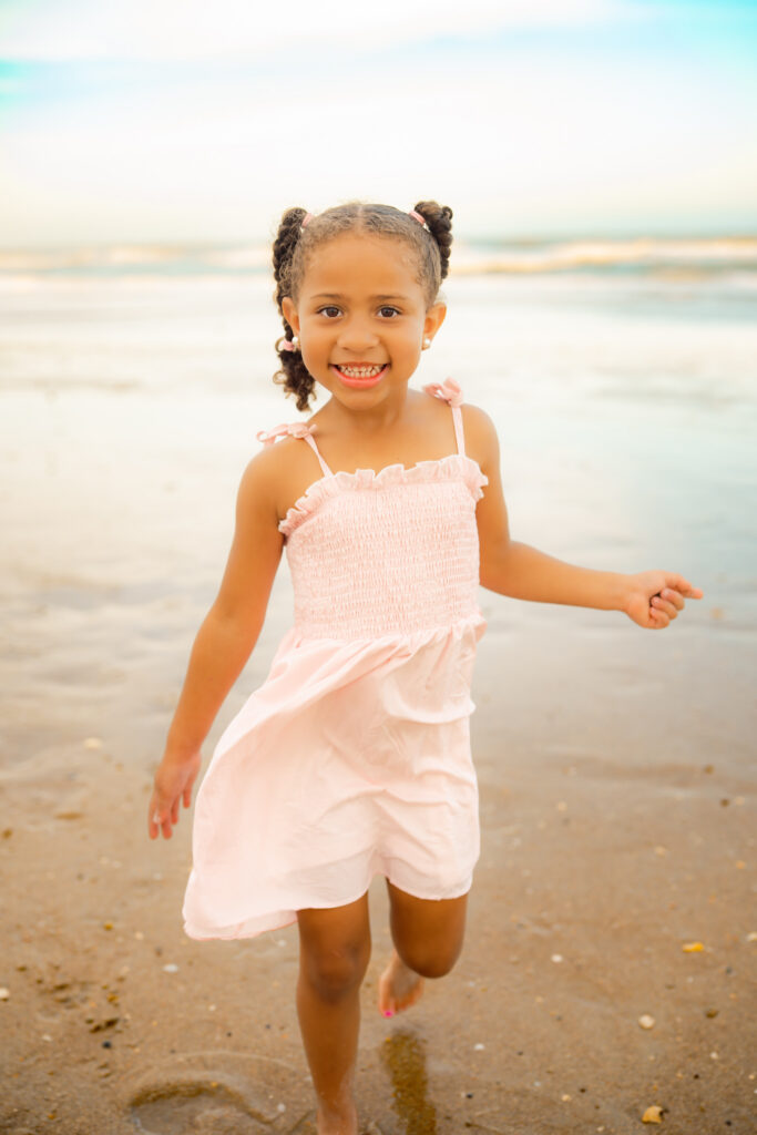 Color photo of a granddaughter playing on the beach and smiling.