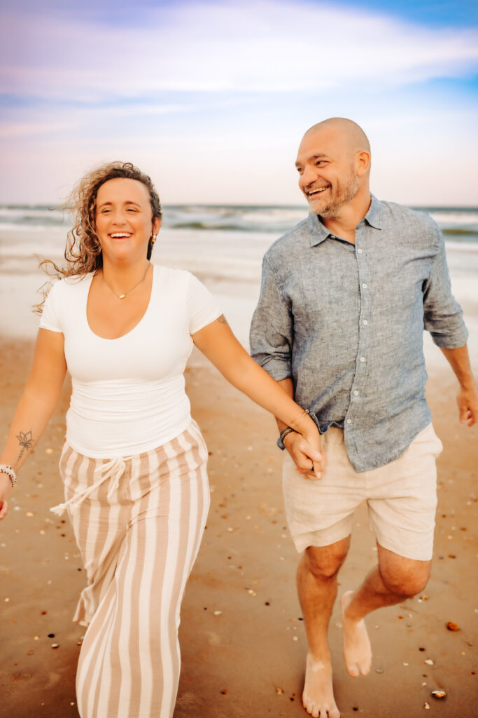 color photo of a dad and his adult daughter laughing and walking along the beach