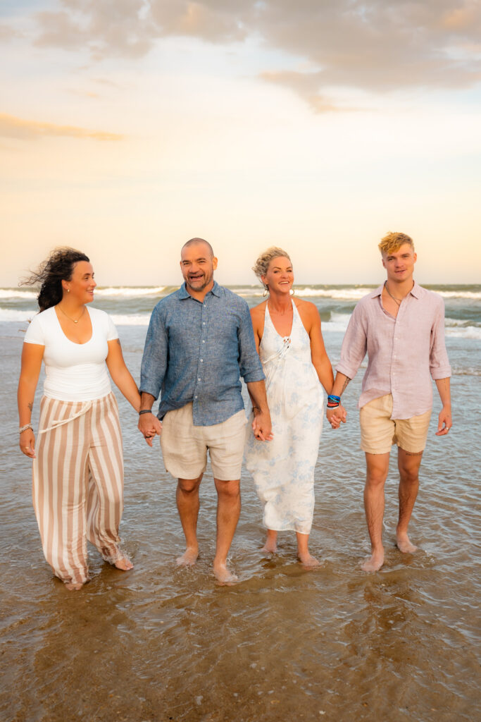 Color family photo walking on the beach holding hands