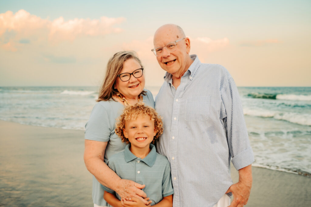 color photo of grandparents and grandson on the beach