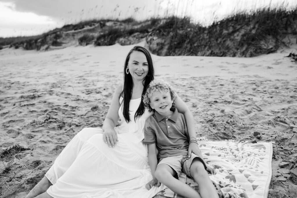 black and white photo of mom and son sitting on the beach