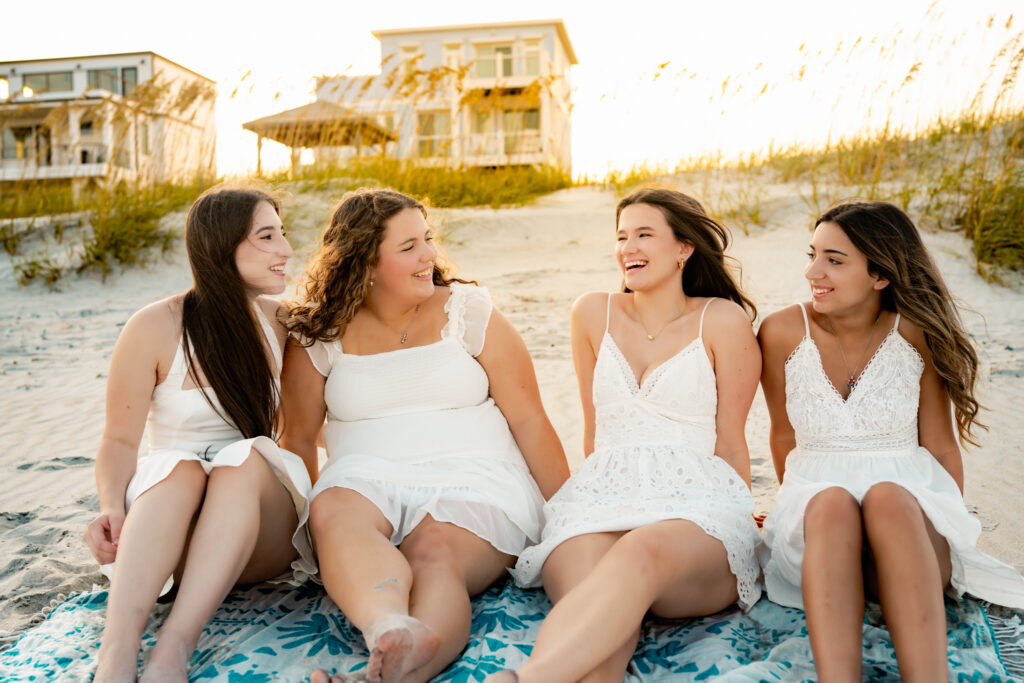 four girlfriends sitting together on the beach