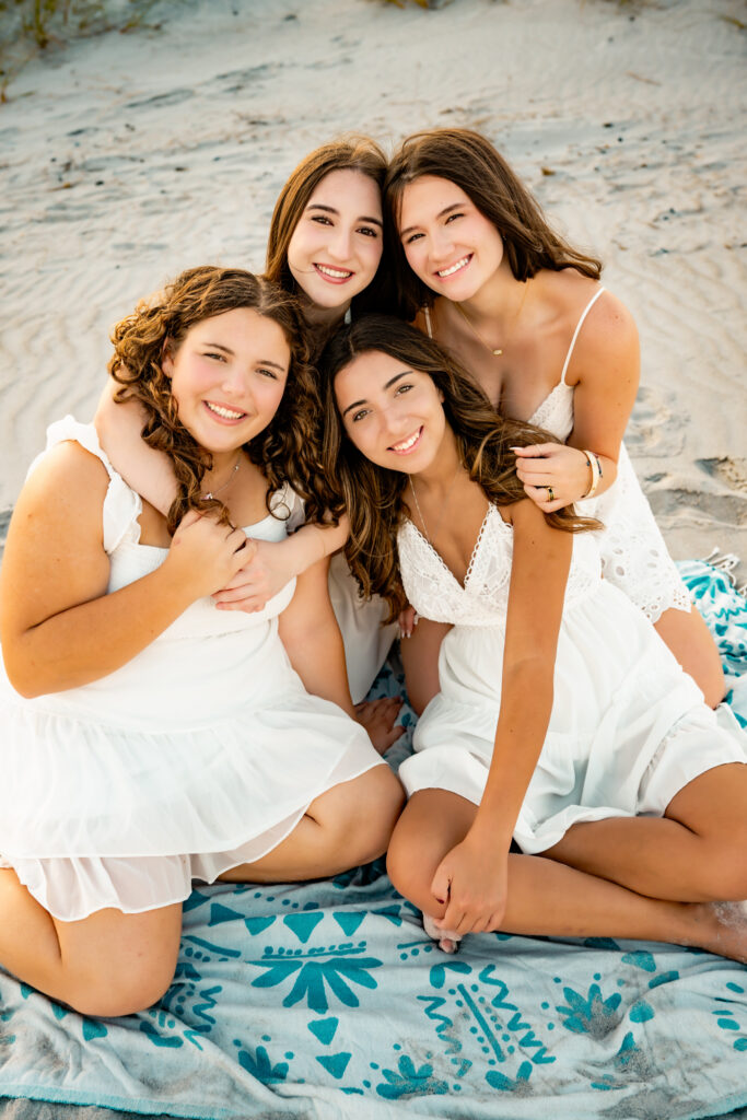 four girlfriends sitting together on the beach
