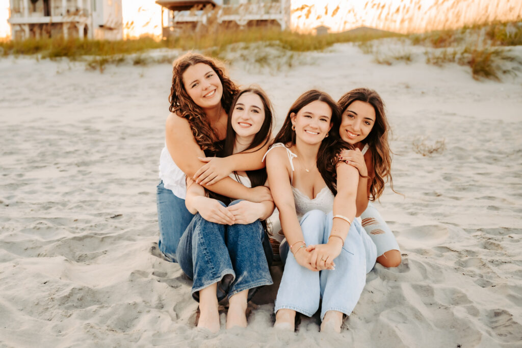 four girlfriends sitting together on the beach