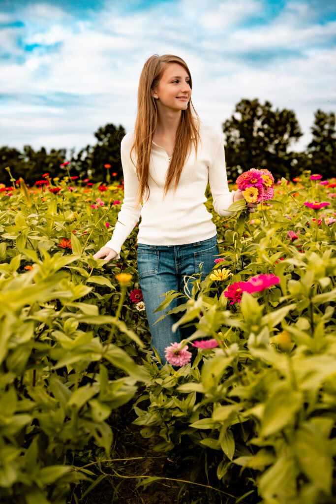 high school senior girl walking in a flower field