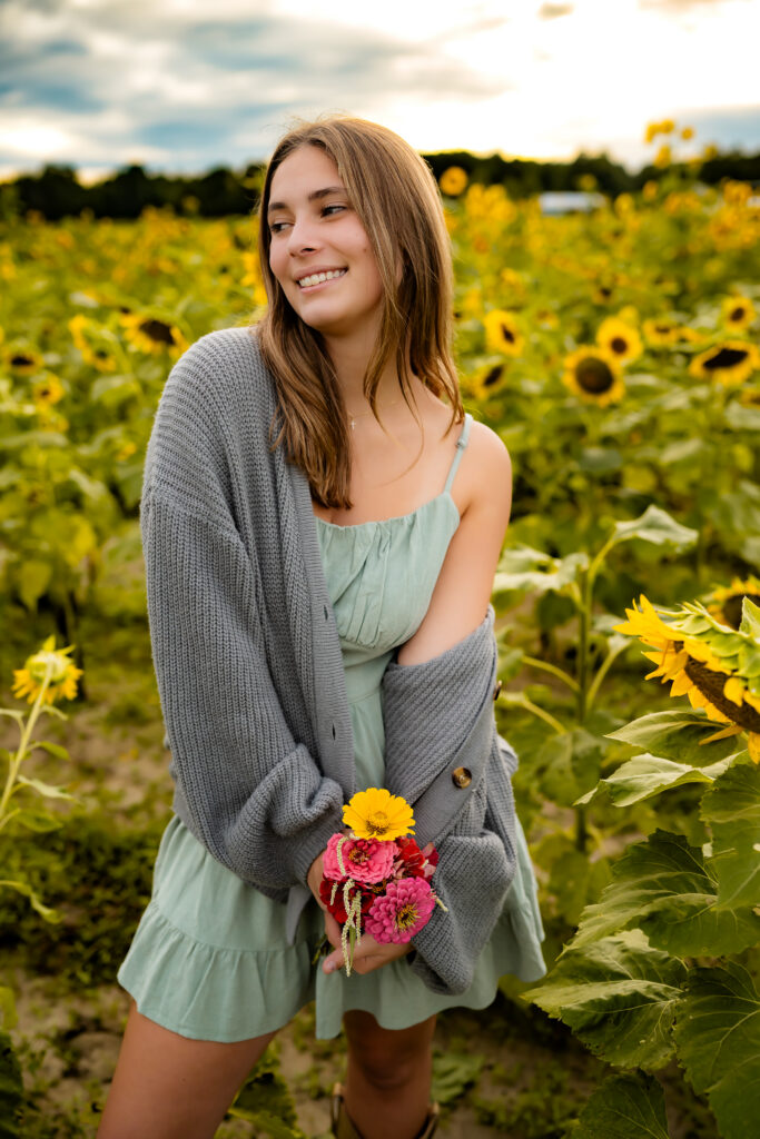 high school senior girl walking in a flower field smiling