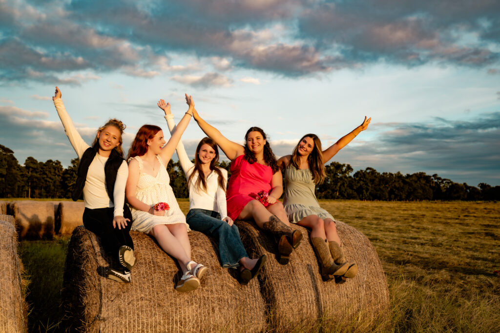 group of high school seniors sitting on a hay bale having fun