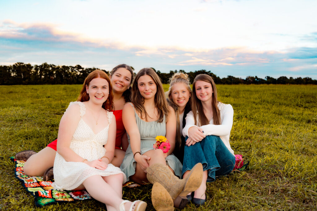group of senior rep team girls sitting together in a flower field smiling