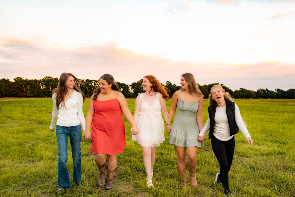 group of senior rep team girls running together in a field at sunset