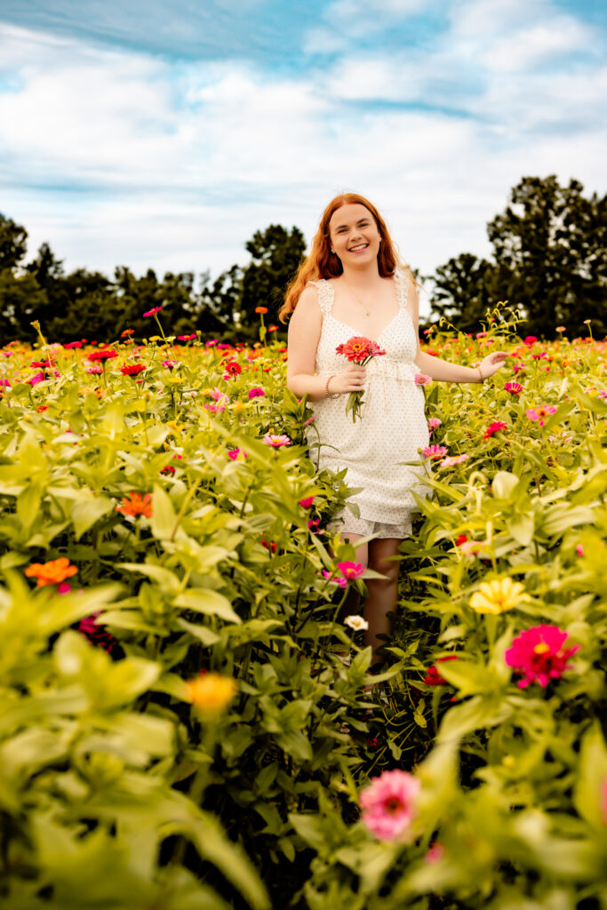 high school senior girl walking in a flower field smiling